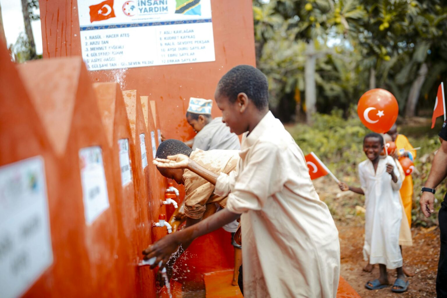 Children enjoying a newly built water station in a community project celebrating partnership and progress.