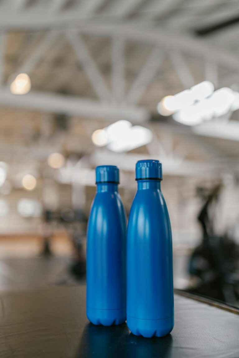 Close-up of two blue water bottles against a blurred indoor background.
