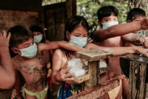 Group of children with face masks using soap and water, promoting hygiene.